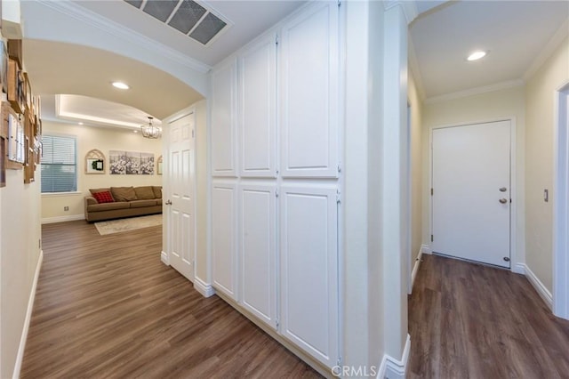 hall featuring ornamental molding, dark wood-type flooring, and a raised ceiling