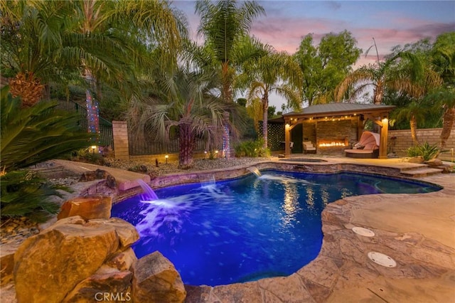 pool at dusk with an in ground hot tub, a patio, and a gazebo