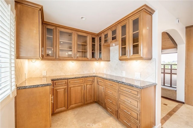 kitchen with light tile patterned flooring, backsplash, and dark stone countertops