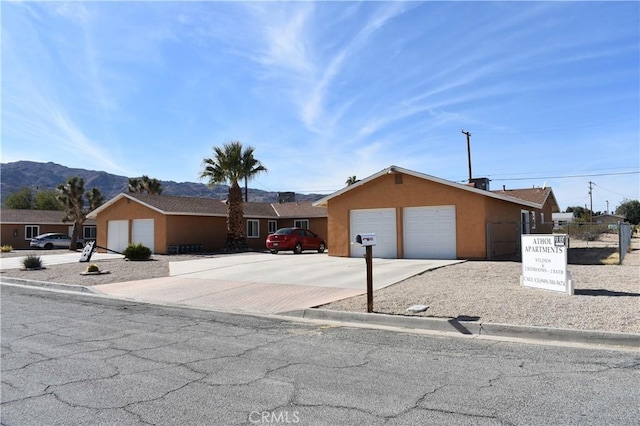 6424 Athol Ave Unit 29, Palms, CA 92277 - view of front of house with a garage, stucco siding, a mountain view, and driveway