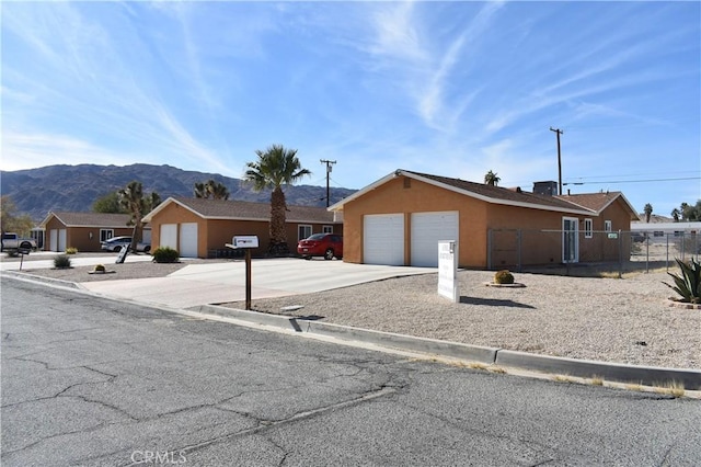 6424 Athol Ave Unit 29, Palms, CA 92277 - view of front of home with fence, a mountain view, concrete driveway, a garage, and stucco siding