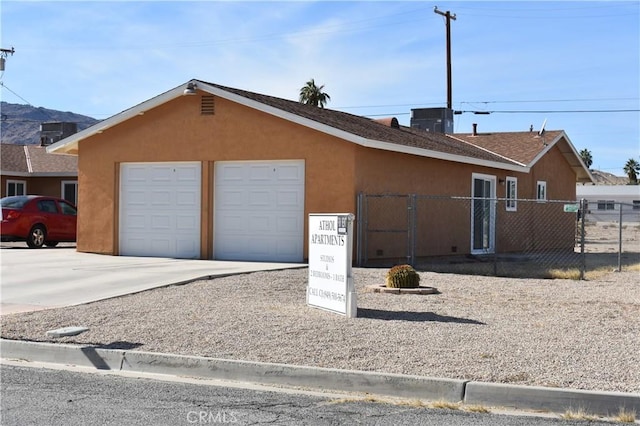 6424 Athol Ave Unit 29, Palms, CA 92277 - view of property exterior with a garage, cooling unit, stucco siding, fence, and concrete driveway