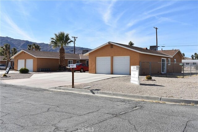 6424 Athol Ave Unit 29, Palms, CA 92277 - view of front of house with a mountain view, fence, an attached garage, stucco siding, and concrete driveway