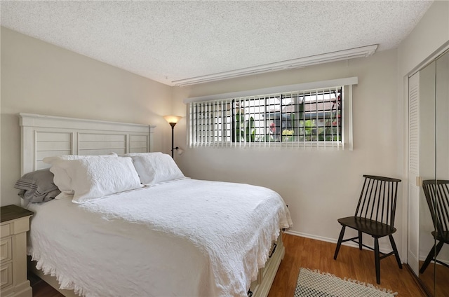 bedroom with a closet, dark hardwood / wood-style flooring, and a textured ceiling