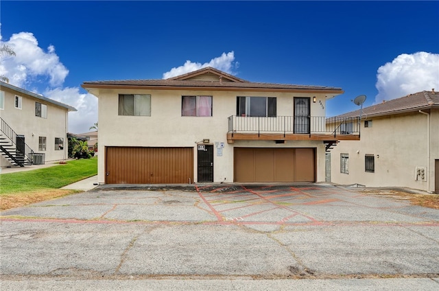3504 Rainbow Ln, Highland, CA 92346 - view of front of property with an attached garage, stucco siding, a balcony, stairway, and driveway