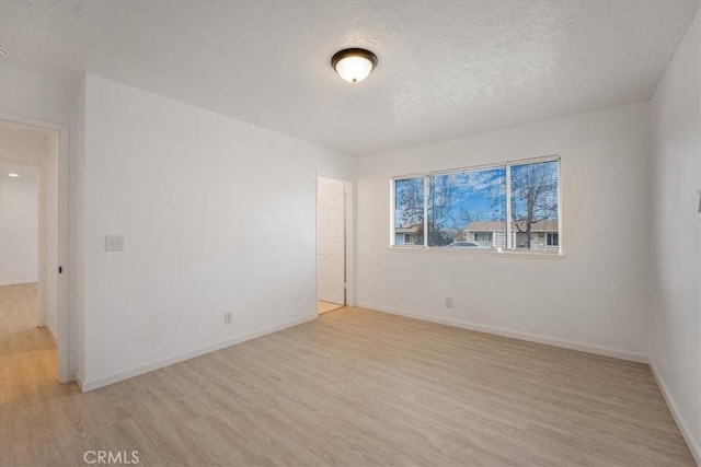 empty room with a textured ceiling and light wood-type flooring