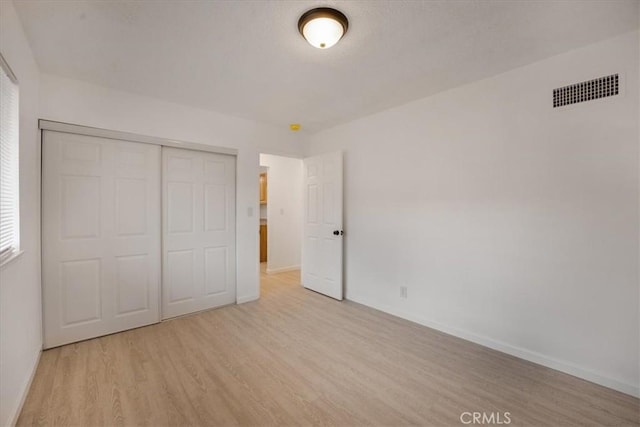 unfurnished bedroom featuring light hardwood / wood-style floors and a closet