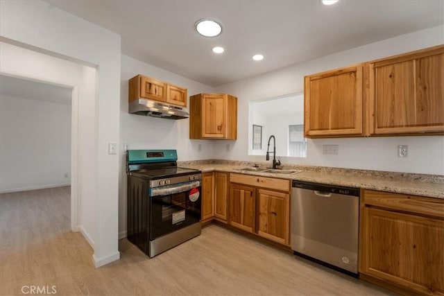 kitchen with stainless steel appliances, light stone countertops, sink, and light wood-type flooring