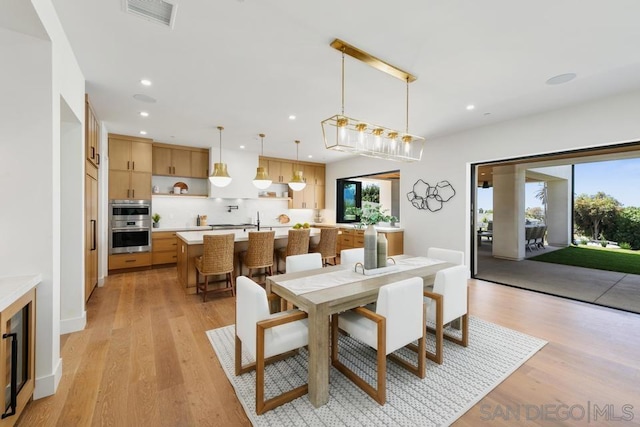 dining room featuring light hardwood / wood-style flooring, beverage cooler, and sink