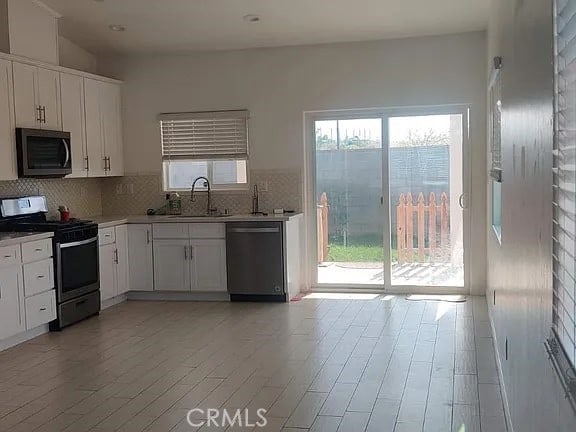 kitchen featuring white cabinets, sink, tasteful backsplash, light hardwood / wood-style floors, and stainless steel appliances