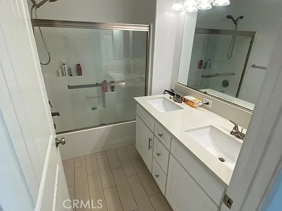 bathroom with shower / bath combination with glass door, hardwood / wood-style floors, and vanity