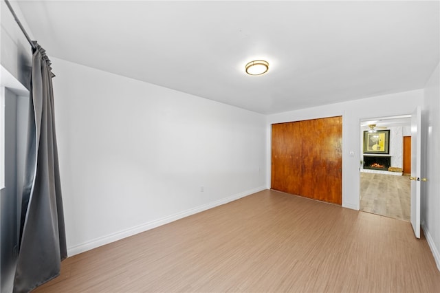 unfurnished bedroom with a fireplace, light wood-type flooring, and a closet