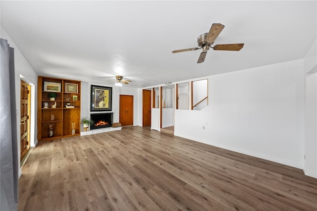 unfurnished living room featuring a fireplace, hardwood / wood-style flooring, and ceiling fan