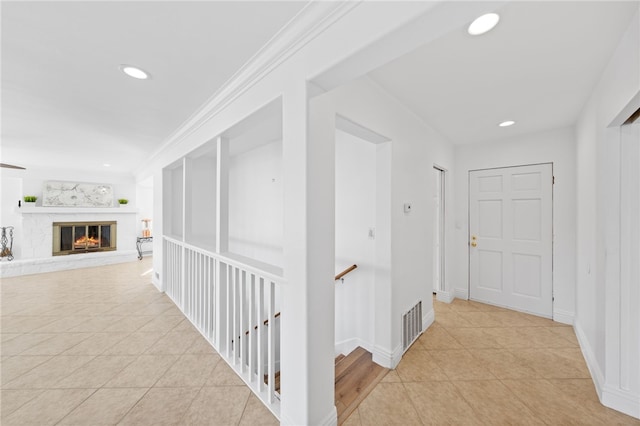 corridor with light tile patterned floors and ornamental molding