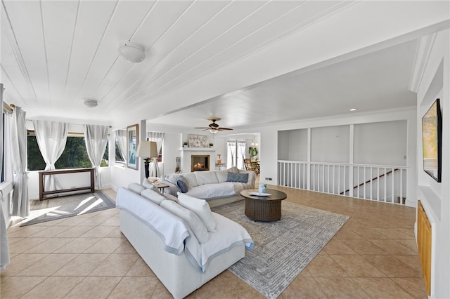 tiled living room with ceiling fan, crown molding, and a wealth of natural light