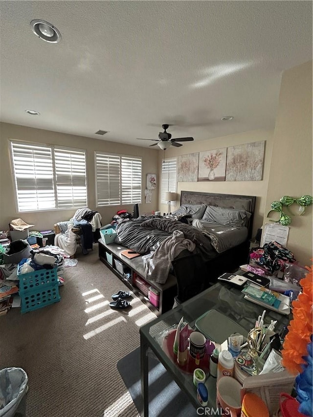 carpeted bedroom with ceiling fan and a textured ceiling
