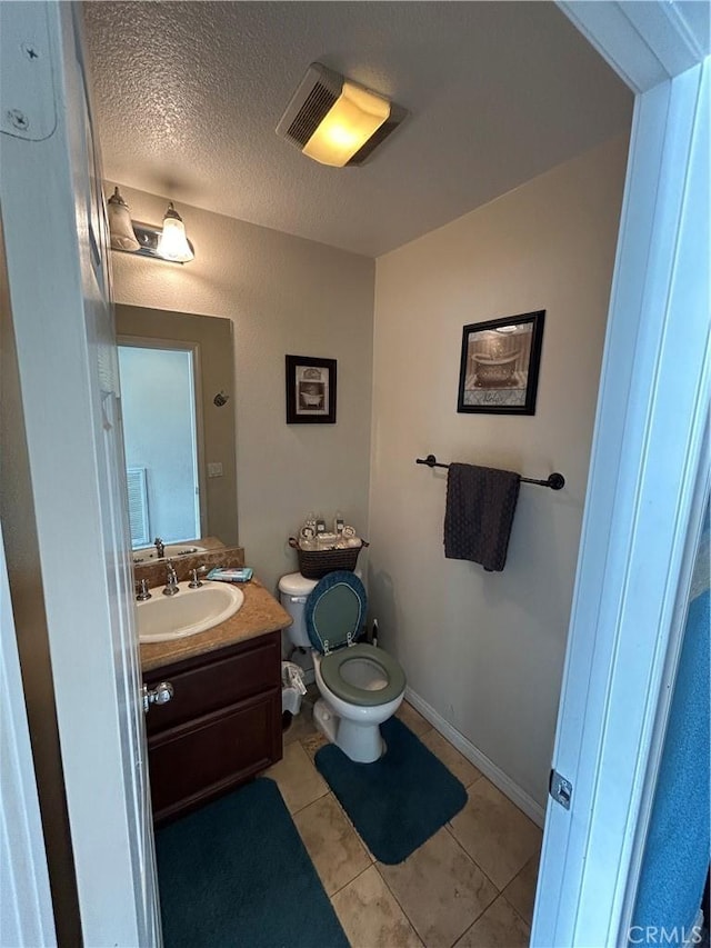 bathroom featuring tile patterned floors, vanity, a textured ceiling, and toilet