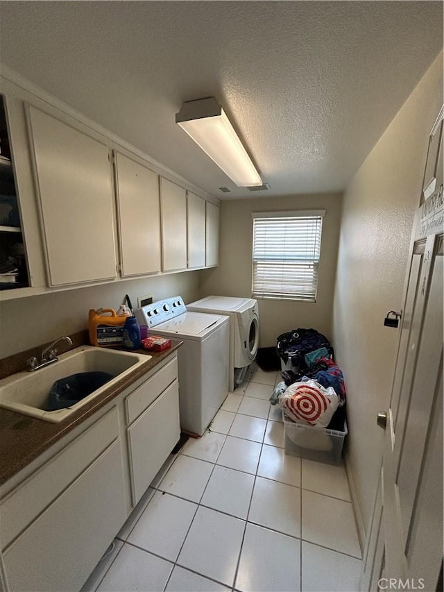 laundry area with cabinets, a textured ceiling, sink, washer and dryer, and light tile patterned flooring