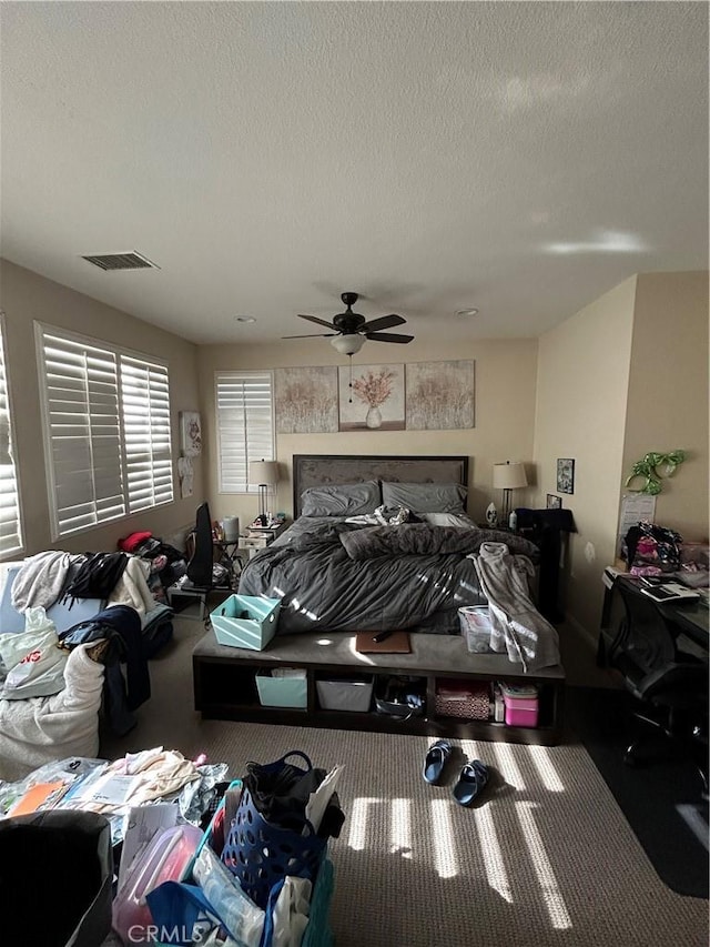 carpeted bedroom featuring ceiling fan and a textured ceiling