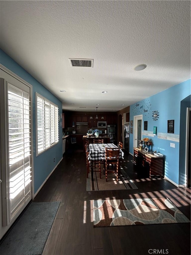 dining area with a textured ceiling and dark hardwood / wood-style floors