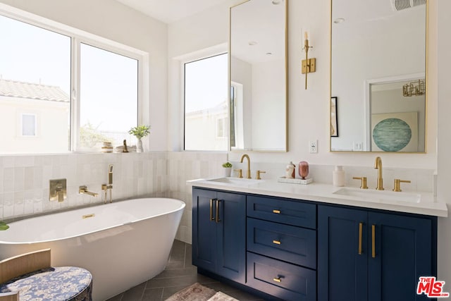 bathroom featuring vanity, a tub to relax in, tile patterned floors, and tile walls