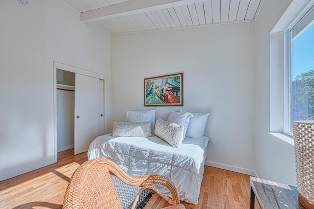 bedroom featuring vaulted ceiling with beams, a closet, and light wood-type flooring