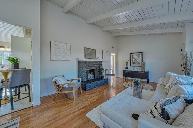 living room with light hardwood / wood-style flooring, beam ceiling, and a fireplace