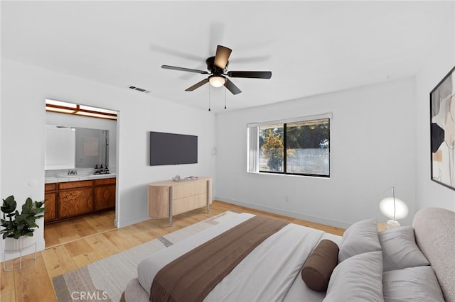 bedroom with light wood-type flooring, ceiling fan, and connected bathroom