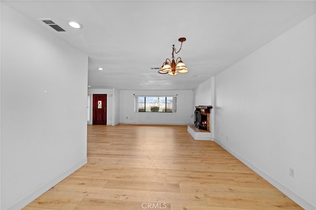 unfurnished living room with light wood-type flooring and a notable chandelier