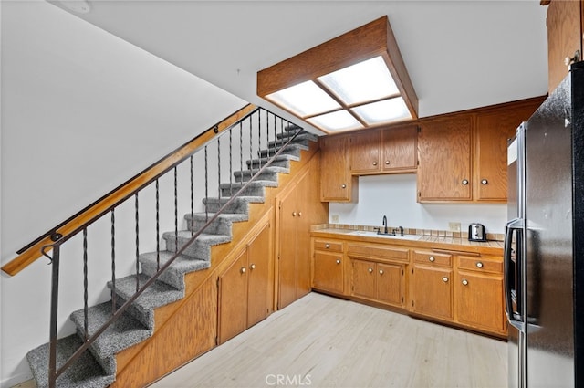 kitchen featuring sink, black refrigerator, and light wood-type flooring