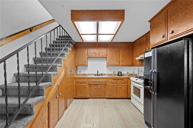 kitchen featuring sink, black fridge with ice dispenser, white stove, and light hardwood / wood-style flooring