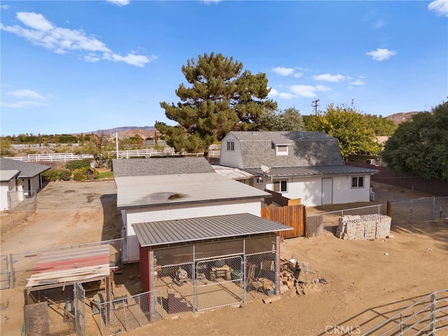 back of property with a mountain view and an outbuilding