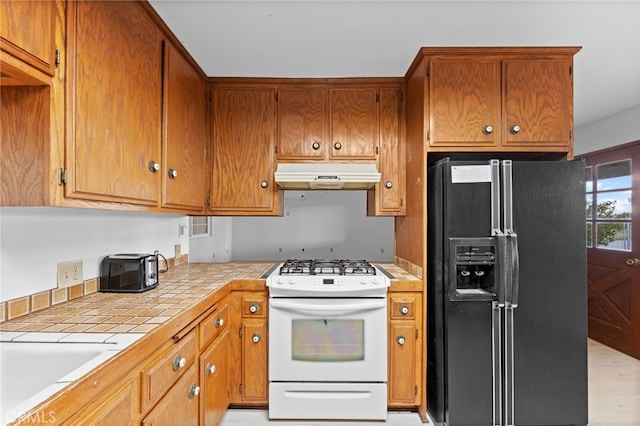 kitchen with white range oven, black fridge, light hardwood / wood-style floors, and sink