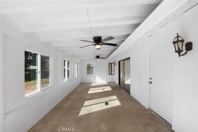 unfurnished sunroom featuring vaulted ceiling with beams, ceiling fan, and plenty of natural light