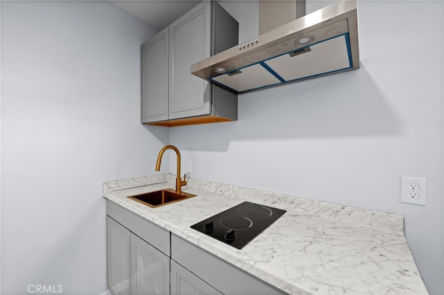 kitchen with gray cabinetry, light stone countertops, sink, wall chimney exhaust hood, and black electric stovetop