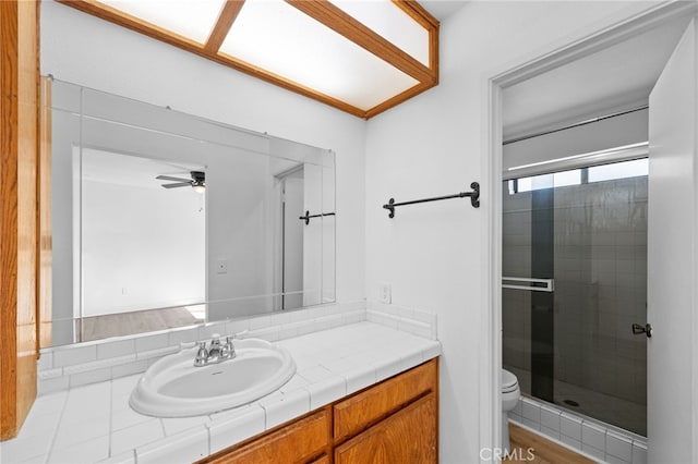 bathroom featuring ceiling fan, toilet, vanity, and walk in shower