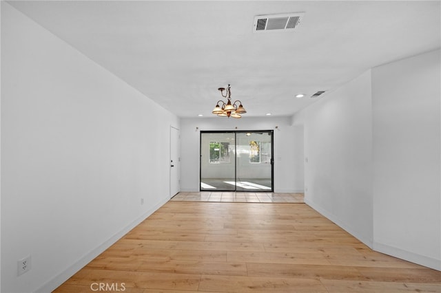 unfurnished room with light hardwood / wood-style flooring and a chandelier