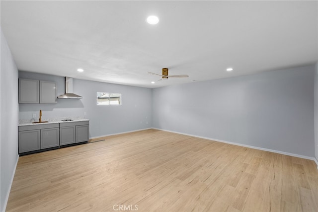 unfurnished living room featuring light hardwood / wood-style floors, ceiling fan, and sink