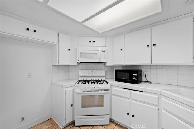 kitchen featuring white cabinetry, tasteful backsplash, tile countertops, white appliances, and light tile patterned floors