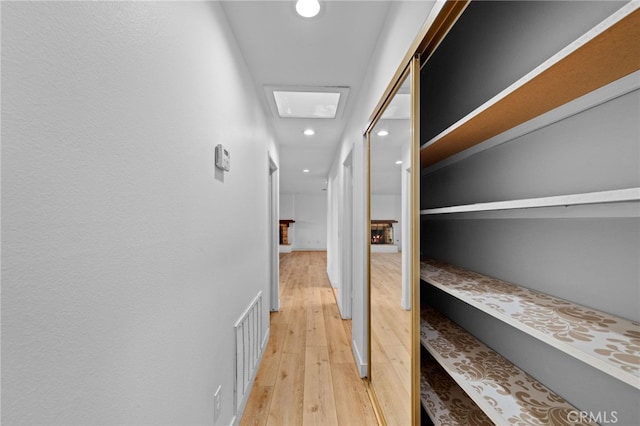 hallway featuring light wood-type flooring and a skylight