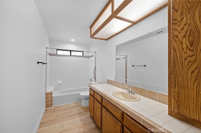 full bathroom with hardwood / wood-style flooring, tiled shower / bath combo, toilet, and vanity