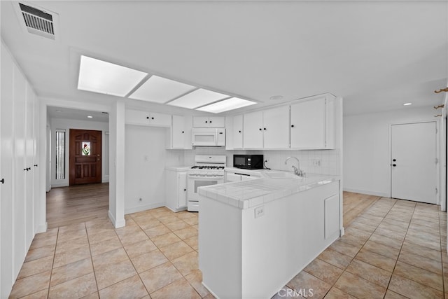 kitchen featuring white cabinets, white appliances, kitchen peninsula, and sink