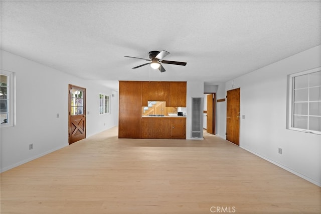 unfurnished living room featuring ceiling fan, light hardwood / wood-style flooring, and a textured ceiling