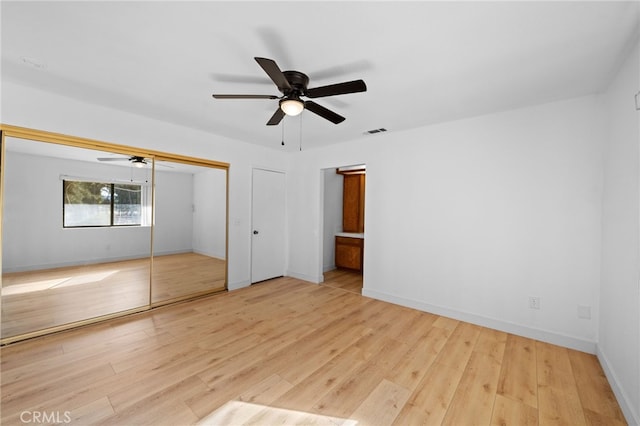 unfurnished bedroom featuring ceiling fan, light hardwood / wood-style floors, and a closet