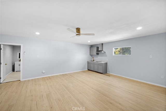 unfurnished living room featuring light wood-type flooring, ceiling fan, and sink