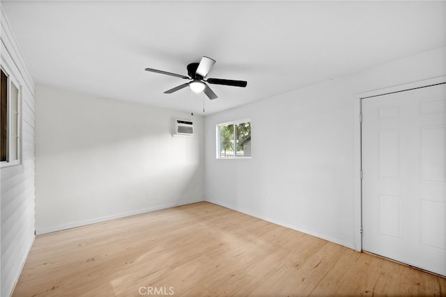 unfurnished room with light hardwood / wood-style flooring, a wall mounted AC, and ceiling fan