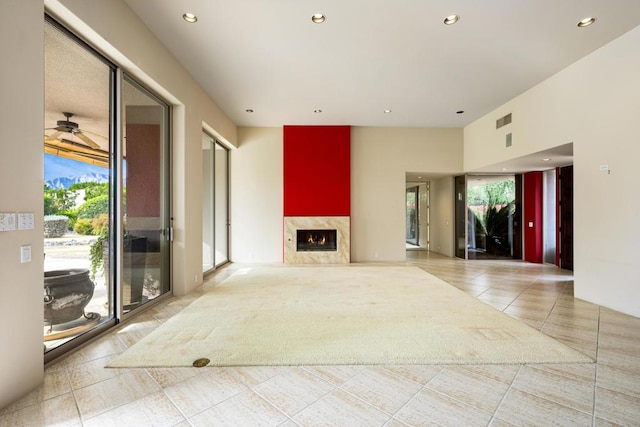 unfurnished living room featuring tile patterned floors, ceiling fan, and a high end fireplace