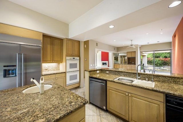 kitchen featuring appliances with stainless steel finishes, dark stone counters, and sink