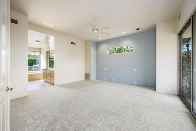 carpeted spare room featuring ceiling fan and a wealth of natural light