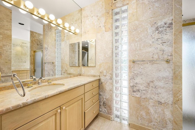 bathroom with an enclosed shower, vanity, and tile walls